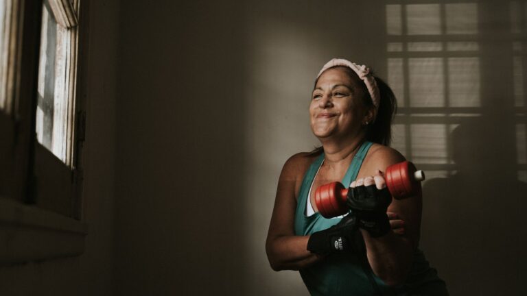 Mulher adulta fazendo treino de força com halteres durante uma rotina de cuidado com a saúde.