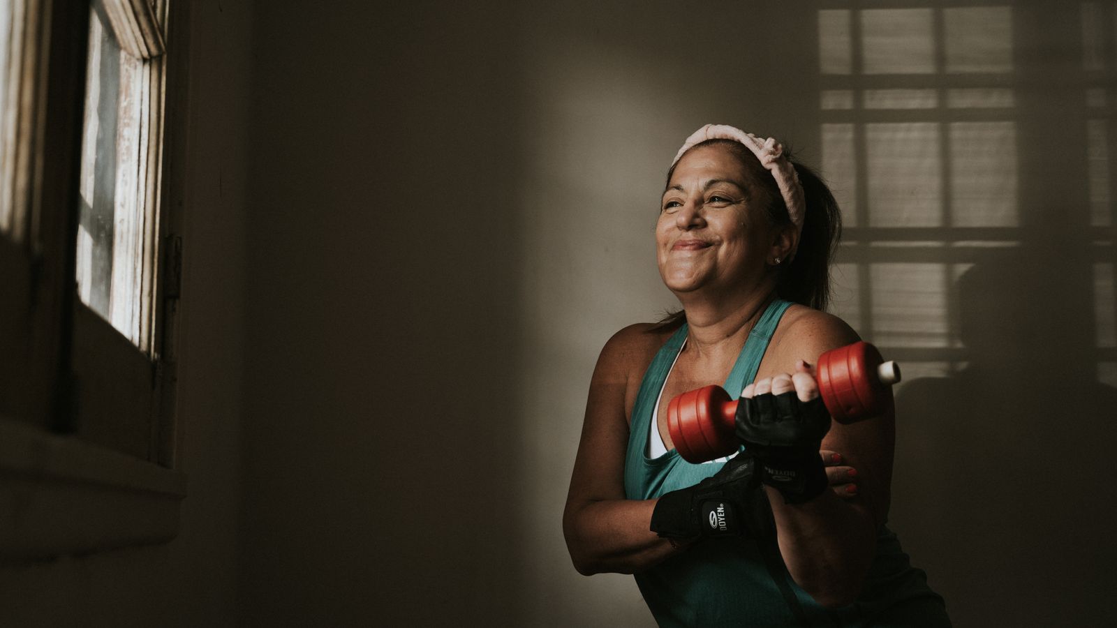 Mulher adulta fazendo treino de força com halteres durante uma rotina de cuidado com a saúde.